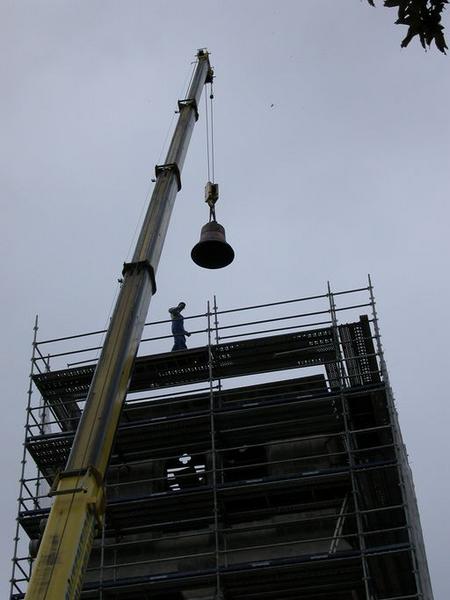Cloche (n°1) élévée à l'aide d'une grue jusqu'au sommet du clocher pour y être installée.