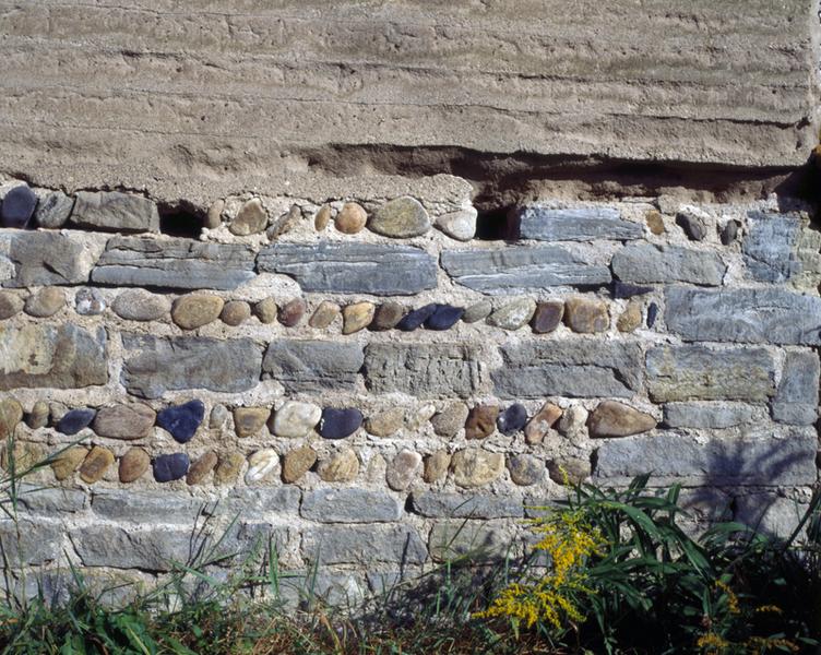 Détail d'un mur en pisé sur solin de moellons et de galets (village de Demolles).