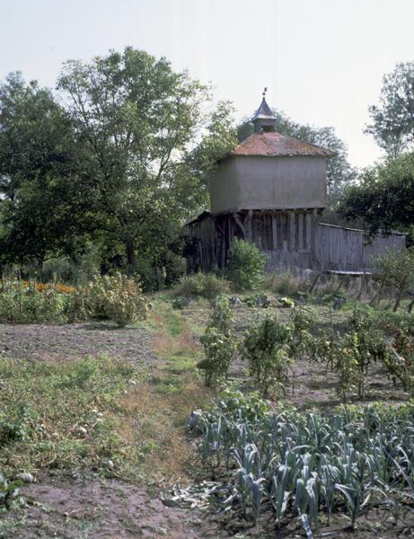 Vue générale d'un pigeonnier à pans de bois sur poteaux, avec base clôturée par un essentage de planches (Le Thuel, Maringues).