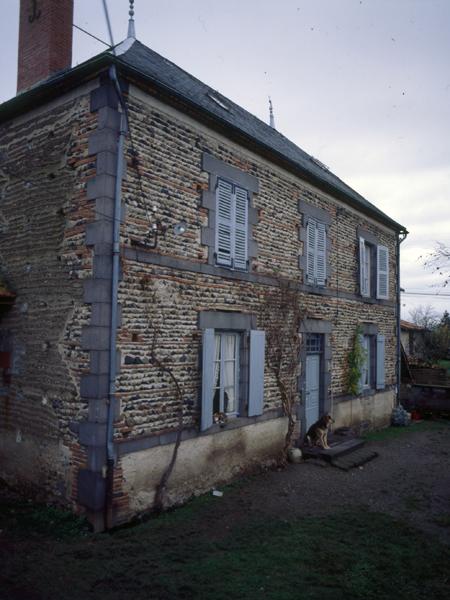 Vue générale d'un logis de ferme en blocage de galets, et encadrements, chaînes d'angles et bandeaux en andésite (Luzillat, village).
