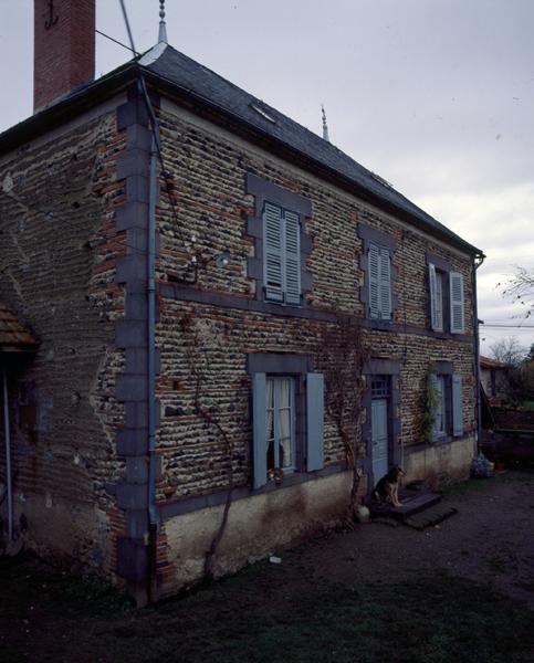 Vue générale d'un logis de ferme en blocage de galets, et encadrements, chaînes d'angles et bandeaux en andésite (Luzillat, village).