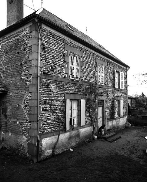 Vue générale d'un logis de ferme en blocage de galets, et encadrements, chaînes d'angles et bandeaux en andésite (Luzillat, village).