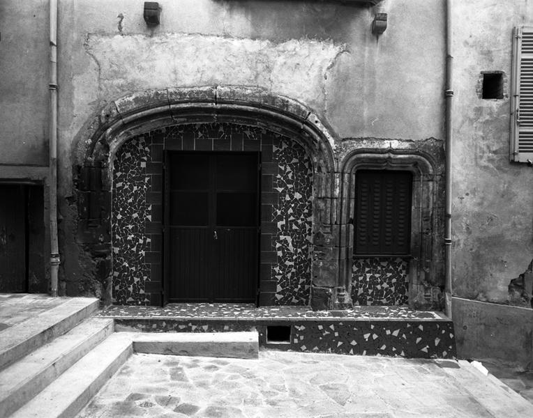 Vue d'une porte à arc en accolade et d'une baie de boutique, remaniées (Maringues, ville).