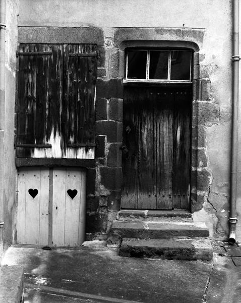 Détail d'une porte accolée à une fenêtre surmontant une entrée extérieure de cave (Maringues, ville).