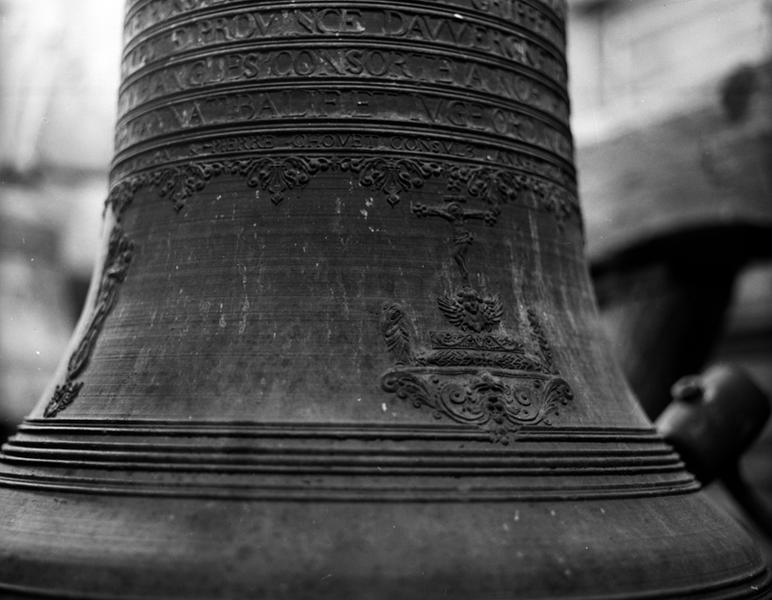 Cloche 2, face postérieure, détail : vase supérieur, trois dernières lignes de l'inscription et frise, et faussure : Calvaire, à droite (à gauche, la Vierge à l'Enfant de la face latérale).