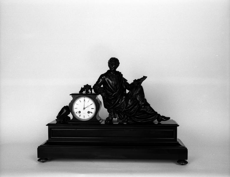 Horloge décorée de la figure de Montesquieu écrivant l'Esprit des lois. La pose un peu artificielle indiquerait que la statuette a été spécialement conçue pour orner ce type d'objet.