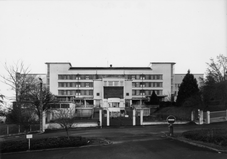 Vue de la façade nord avec l'entrée principale très saillante et la loge circulaire du concierge encadrée par deux escaliers.