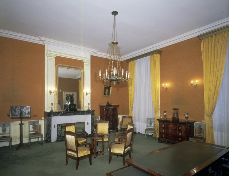 Bureau du Procureur général. Angle nord-est, avec bureau en premier plan, fauteuils autour d'une table en guéridon au-dessus desquels est suspendu le lustre, à droite : commode sur laquelle prennent place les vases et l'horloge, dans le fond, secrétaire à abattant.