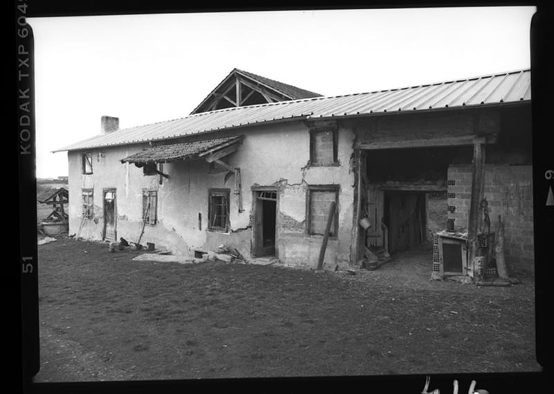 Vue de la maison-bloc : façade principale des deux logis avec l'auvent protégeant l'entrée de cave et la porte de l'ancienne grange.