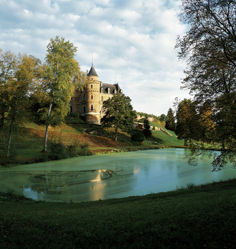 Vue d'ensemble du château et du parc avec l'étang au premier plan.