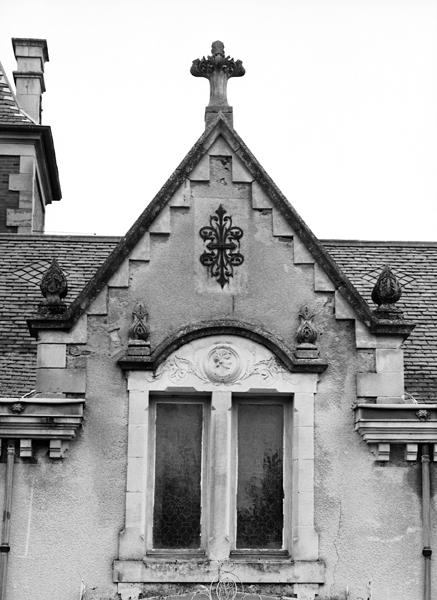 Détail de la baie centrale passante en lucarne à linteau sculpté, en façade principale de la villa.