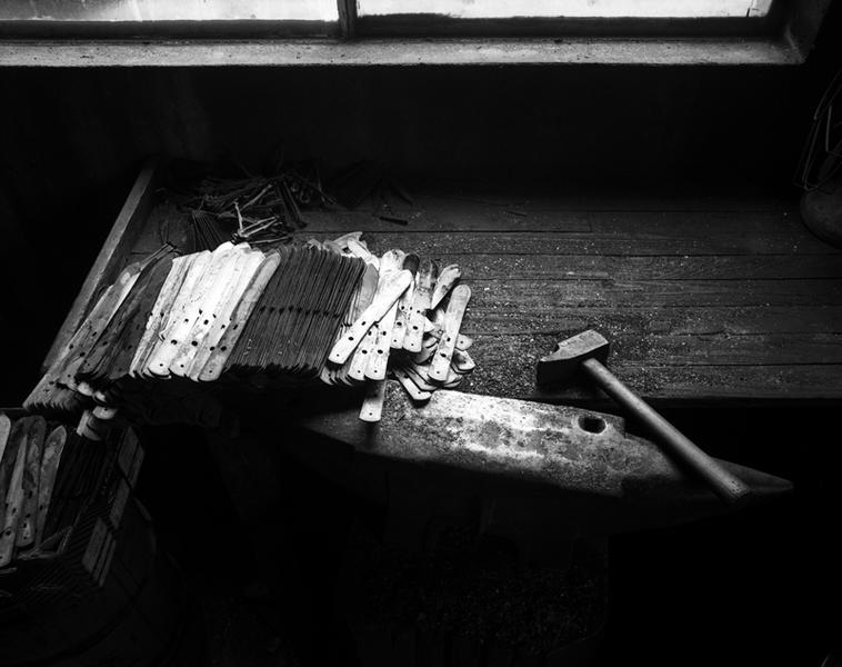 Atelier de trempe : établi avec lames, ressorts, marteau et enclume bigorne.