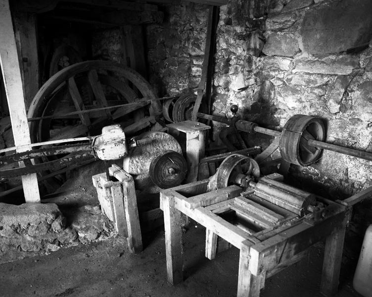 Vue intérieure du rez-de-chaussée : courroies, poulies et axe de transmission du moulin-scierie.