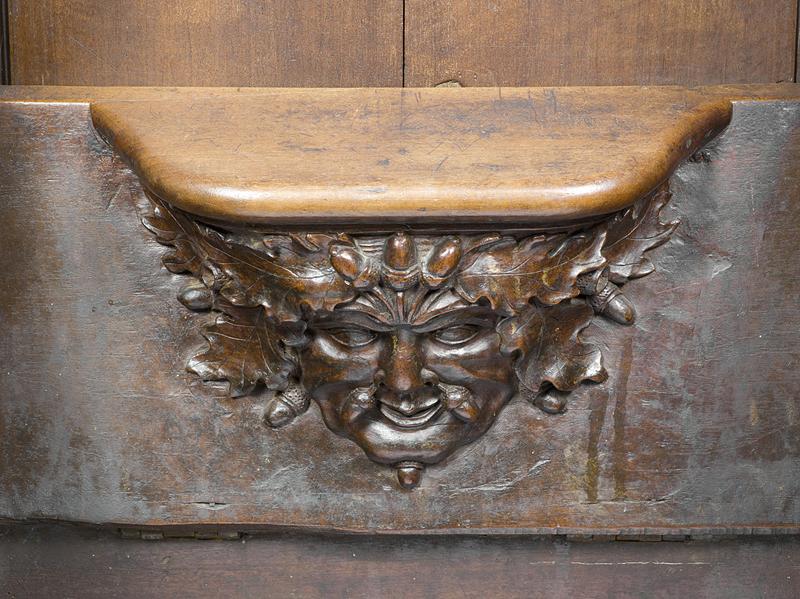 Vue de détail d'une miséricorde : mascaron aux glands et feuilles de chêne