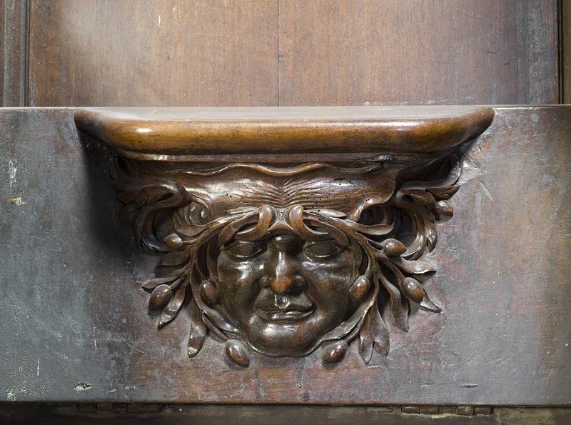 Vue de détail d'une miséricorde : mascaron au rameaux d'olivier