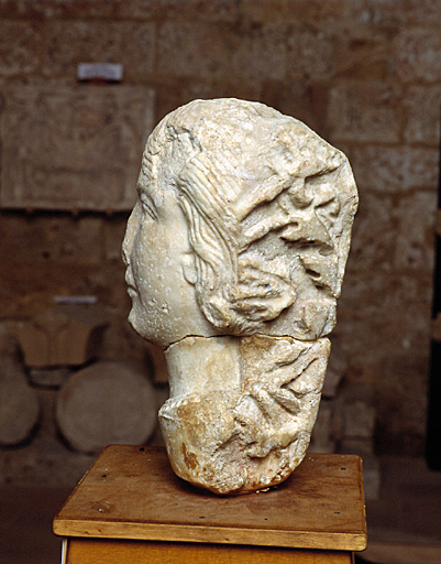 Tête féminine sculptée à l'époque romane dans un fragment de marbre antique déjà travaillé.