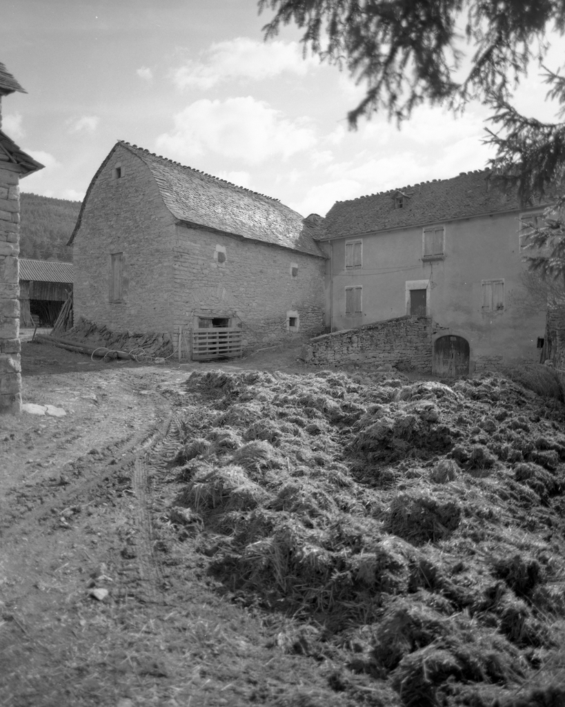 Vue d'ensemble d'une ferme de plan en L à Julhers : logis daté 1830 sur étable datée 1702