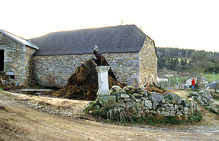 Vue d'ensmble de la ferme prise de l'oues avec une croix de chemin en premier plan