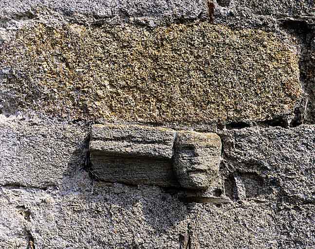 Tête sculptée en remploi dans l'élévation sud de la chapelle