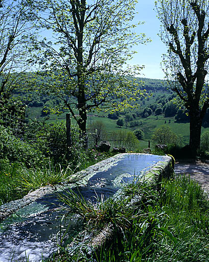 Paysage de la Margeride avec une fontaine abreuvoir en premier plan
