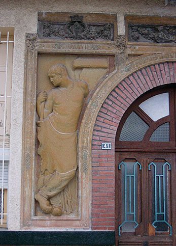 Détail du bas-relief gauche du portail (1901), signé Gustave Violet et représentant le Travail.