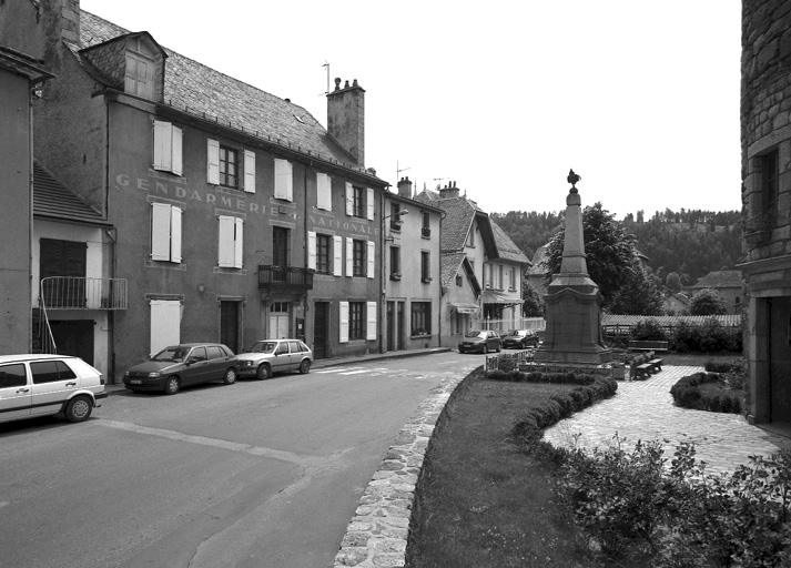 Vue d'ensemble de la place du Souvenir prise d'est en ouest, avec l'ancienne gendarmerie et le monument aux morts