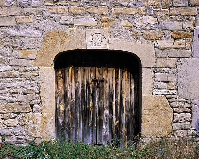 Porte batarde présetant une clef datée 1884 et un emblème d'artisan.