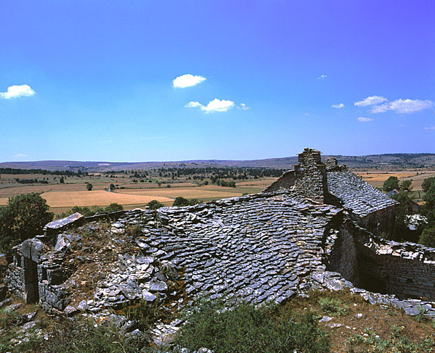 Vue d'ensemble de l'entrée de la grange et des toits de la ferme prise du nord-est. A l'arrière plan, le causse de Sauveterre.