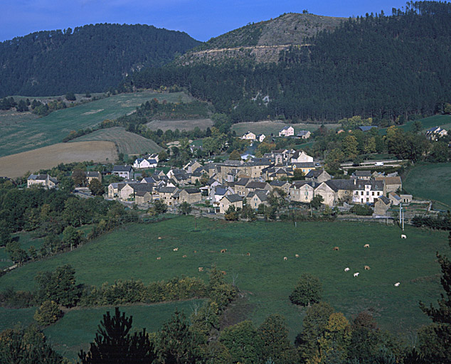 Vue d'ensemble du village prise du sud-est, en arrière-plan, le causse de Mende et le site de l'ancien château fort de Chapieu.