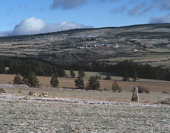 Vue éloignée du village de La Fage prise du sud vers le nord à partir de la Cham des Bondons avec un menhir en premier plan.