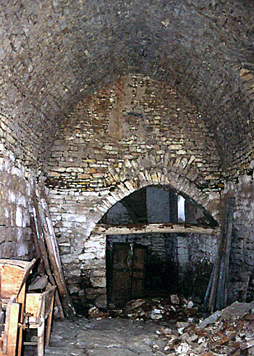 Vue d'ensemble de l'intérieur de la grange-étable, le plancher a disparu.