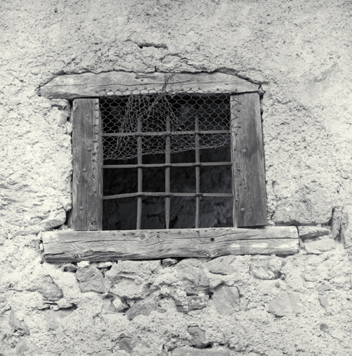 Le Serre. Ferme parcelle 999. Façade sud. Fenêtre. Exemple de chambranle en bois muni d'une grille, assemblé avant intégration dans la maçonnerie.
