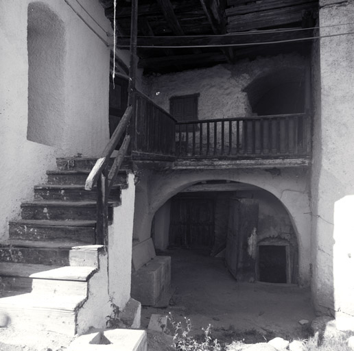 Court ouverte. Vue frontale montrant le départ de l'escalier d'un bâtiment sud, l'entrée de la cave, et au premier étage une court secondaire voûtée en berceau. ; Ferme 442. Court ouverte. Vue frontale montrant le départ de l'escalier d'un bâtiment sud, l'entrée de la cave, et au premier étage une court secondaire voûtée en berceau.