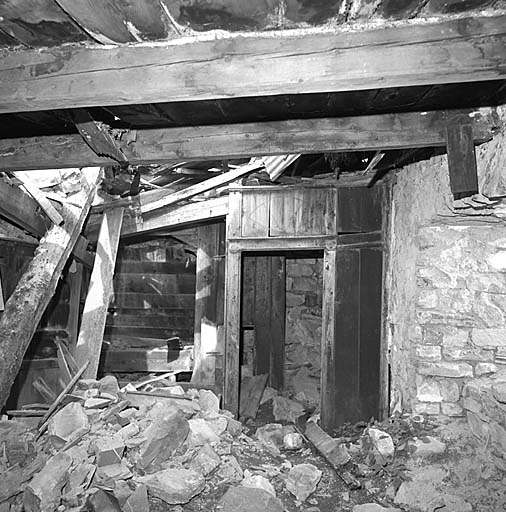 Vue intérieure du logis. Tambour où s'ouvrent la porte extérieure, la porte de la cuisine et celle de l'escalier qui conduit à la chambre au premier étage.