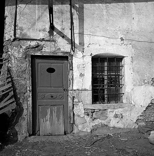 Parcelle 250. La porte du logis a un chambranle en bois. Noter l'ouverture ovale dans le panneau supérieur et les motifs décoratifs : rosace, étoile à cinq branches.