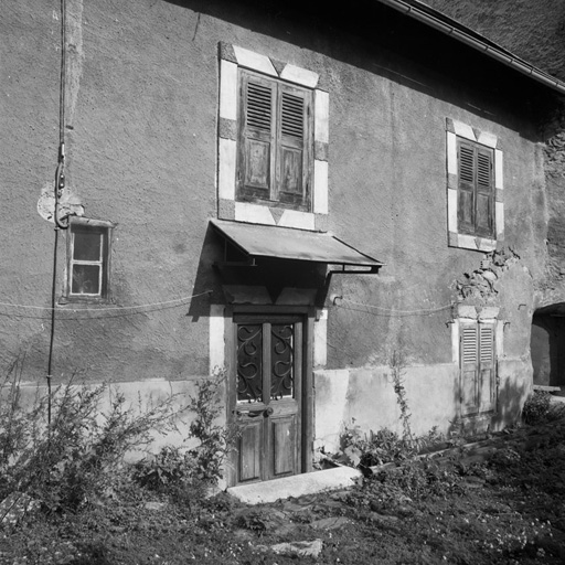 Chef-lieu. Parcelle 596. Noter les encadrements des fenêtres en relief et peints ; l'auvent en tôle protégeant la porte.