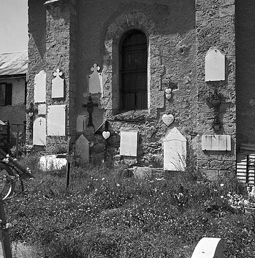 Croix et inscriptions funéraires contre le mur de l'église.