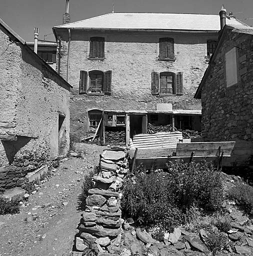 Parcelle 70. Façade sud. Noter l'ordonnance des fenêtres à volets et balconnets en fer forgé. Le toit à deux croupes est surmonté d'épis de faîtage. De part et d'autre de la porte d'entrée, blettes de fumier de moutons protégées par un auvent.