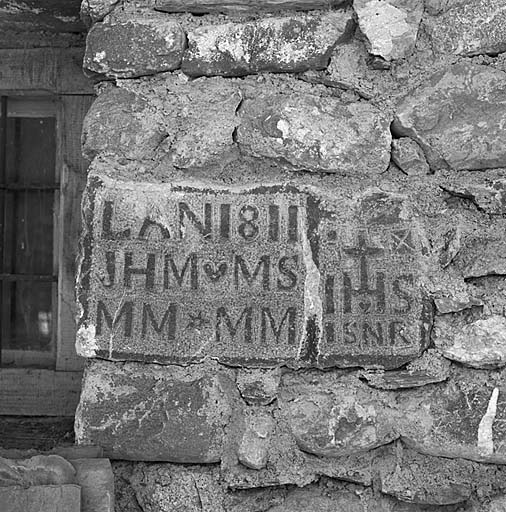 Inscription sculptée en léger relief sur un bloc de granit et placée dans un piédroit de fenêtre.