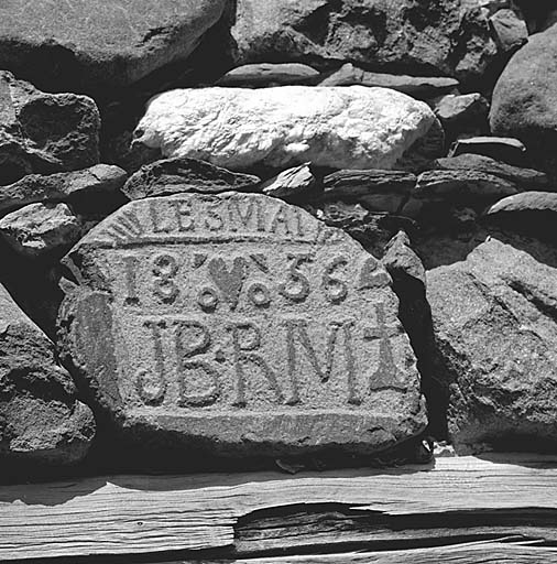 Parcelle 770. Bloc de granit sculpté en léger relief placé au-dessus du linteau de la cuisine. Inscription : le 3 mai 1856 JB.RM.