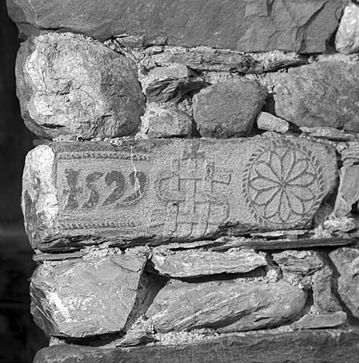 Parcelle 395. Dans un chaînage d'angle, inscription bicolore sculptée en léger relief sur un bloc de granit. Date : 1559.