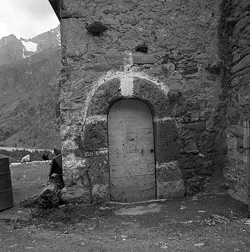 Chambre ménagère. La porte d'entrée. Le chambranle en tuf est souligné de blanc et surmonté d'une croix et la menuiserie recouverte de tôle.