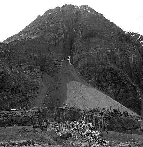 Mur défensif. Vue rasante de l'aile droite prise de la route D 89, au nord-ouest, vers le torrent. Au fond, le massif du Lasseron. En bas, à gauche, la toiture du casernement léger de l'ouvrage des Aittes.