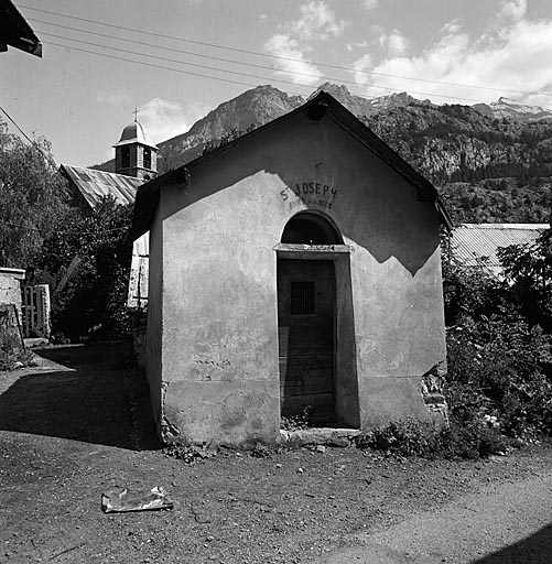 Pignon sud-ouest. Inscription peinte au-dessus de la porte : St Joseph priez pour nous.