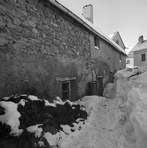 Une rue en hiver au Chazelet. Près de la porte le brancard utilisé pour sortir le fumier qui est entreposé à proximité de la maison avant d'être épandu dans les champs au printemps.