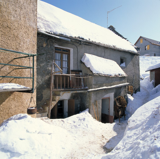 Façade sud. Vue prise au mois de février. ; Le Villar d'Arène. Vue prise au mois de février. Trace dans la neige jusqu'à la porte du porche, contre lequel s'appuie un brancard en bois avec lequel on sort le fumier de l'écurie.