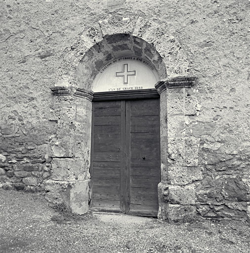 La porte d'entrée. Inscription : l'église de Sainte-Croix a été rebâtie l'an de grâce 1865.