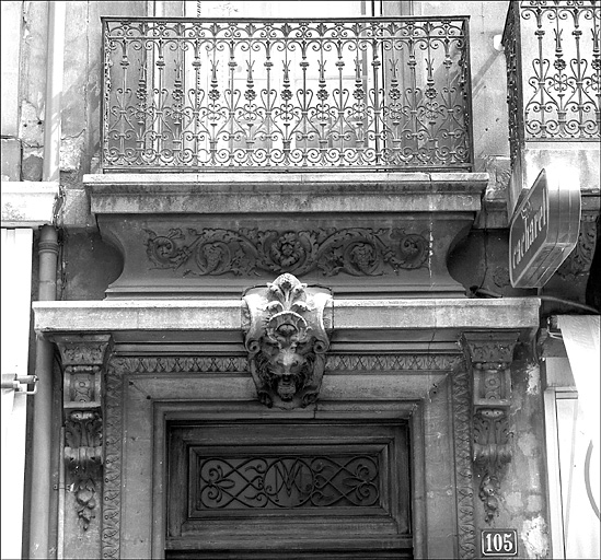 Immeuble 105 rue d'Antibes. Imposte et couronnement de la porte d'entrée, garde-corps en fonte du 1er étage.