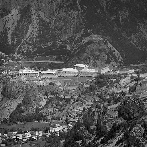 Ensemble du fort vu du sud. De gauche à droite : magasin à poudre T, arsenal S, garage P, casernes K et I, ancienne chapelle E et pavillon D, caserne B et pavillon A de la porte Royale. En avant, vallon et village de Fontchristiane. A l'arrière-plan : fort des Salettes.