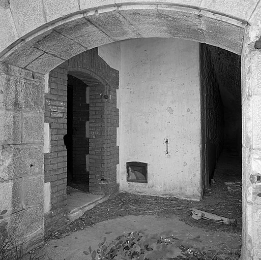 Bâtiment X (magasin à poudre mi-caverne). Entrée et vue intérieure. A gauche, la porte d'accès au vestibule de la chambre à poudre, à droite la galerie enveloppe.